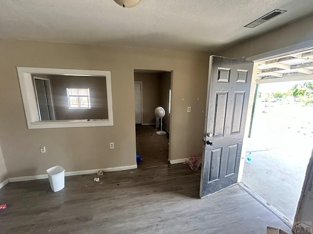 foyer entrance with wood finished floors, plenty of natural light, baseboards, and a textured ceiling