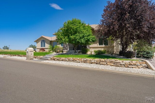 obstructed view of property with a tile roof, a front lawn, and stucco siding