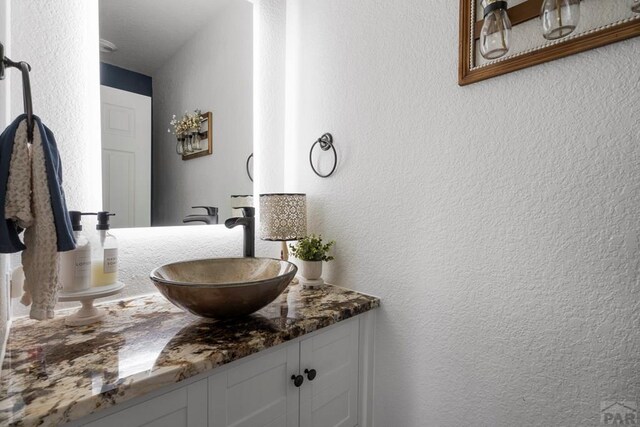 bathroom featuring a textured wall and vanity