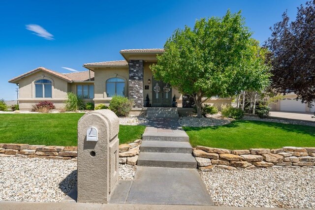 mediterranean / spanish home featuring a front lawn, a tile roof, and stucco siding