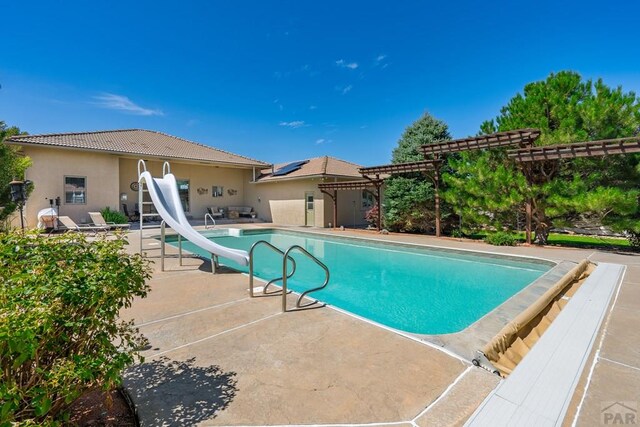 pool featuring a water slide, a pergola, and a patio