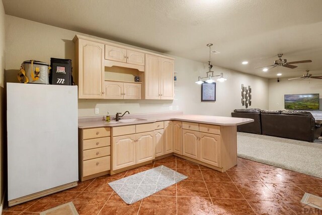 kitchen featuring open floor plan, freestanding refrigerator, hanging light fixtures, light countertops, and a sink