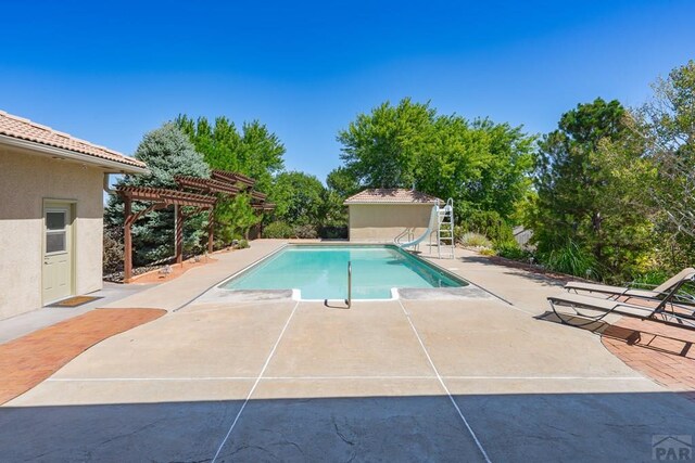 pool with a water slide, a patio area, and a pergola