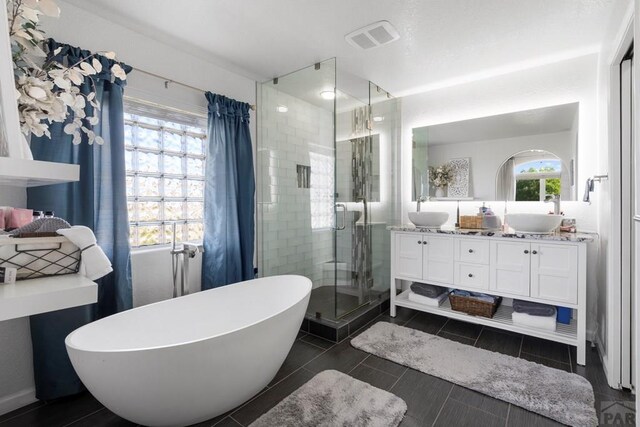 full bathroom with a freestanding tub, a sink, a shower stall, and double vanity