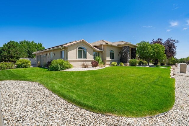 view of front of home featuring a front yard, an attached garage, and stucco siding