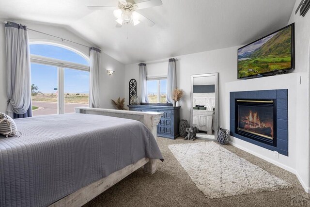 bedroom with vaulted ceiling, carpet floors, a tile fireplace, and a ceiling fan