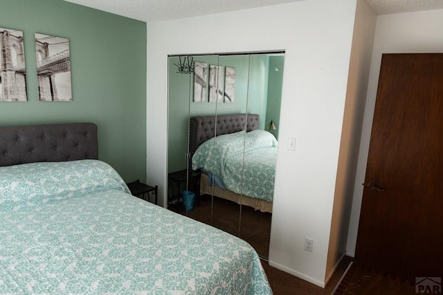 bedroom with a closet, carpet flooring, a textured ceiling, and baseboards