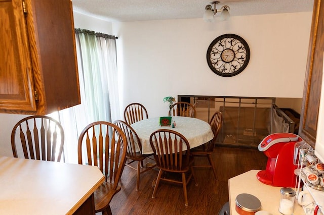 dining area featuring a textured ceiling, a healthy amount of sunlight, and dark wood-style floors