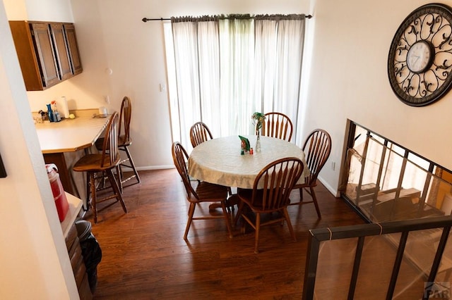 dining space with dark wood finished floors and baseboards