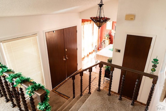 staircase featuring a textured ceiling and vaulted ceiling