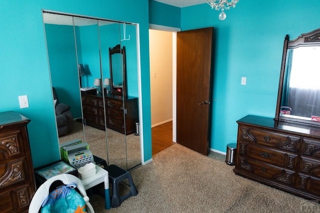 carpeted bedroom with a closet and baseboards