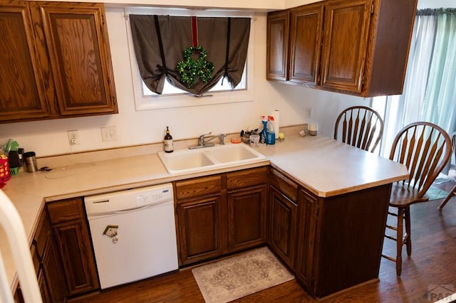 kitchen with a sink, a kitchen bar, white dishwasher, and light countertops