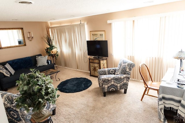 carpeted living room with visible vents, a textured ceiling, and a healthy amount of sunlight