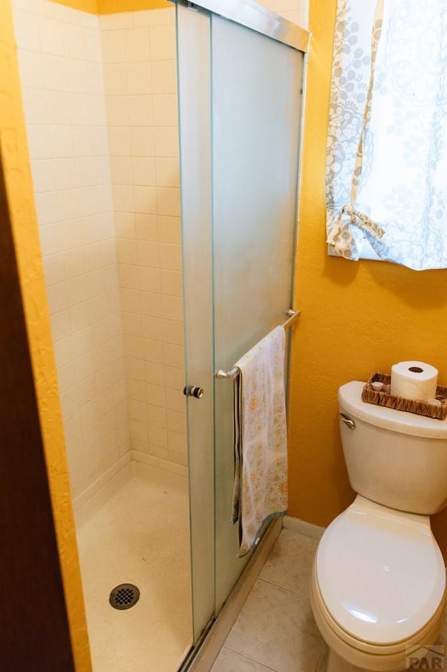 full bathroom with tile patterned flooring, toilet, baseboards, and a stall shower