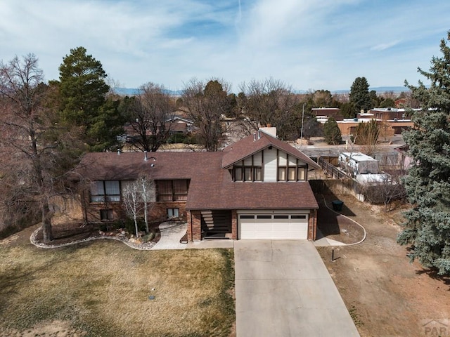 view of front of home featuring brick siding, a shingled roof, a front lawn, driveway, and an attached garage