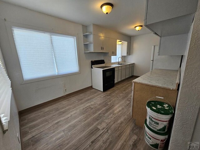 kitchen with dark wood-type flooring, range with electric cooktop, a sink, baseboards, and open shelves