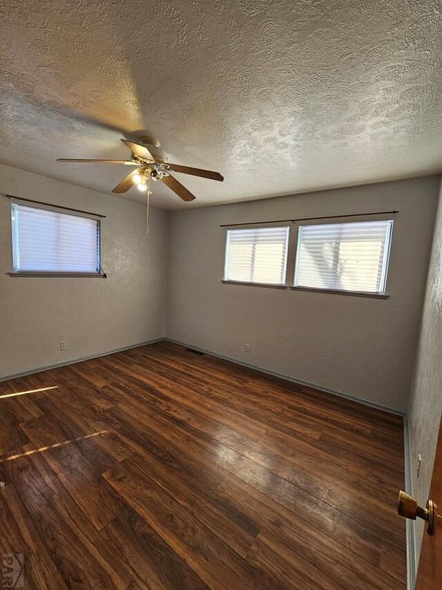 spare room with a textured ceiling and dark wood-type flooring