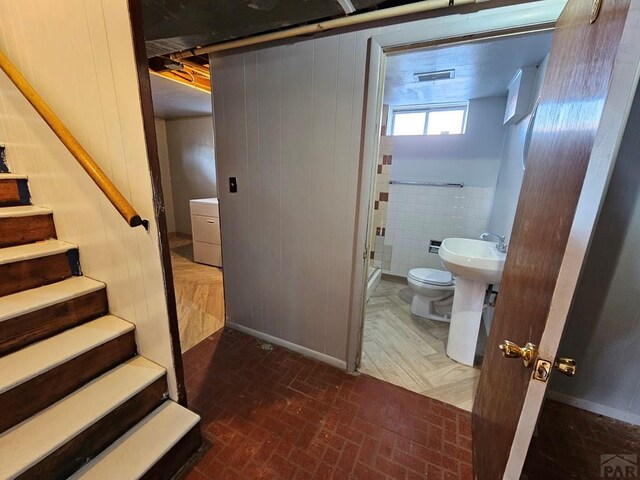 bathroom featuring brick floor, a sink, and toilet