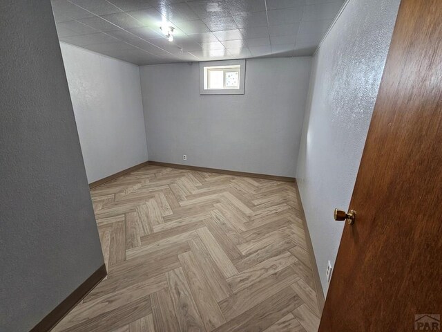 below grade area with baseboards and a textured wall