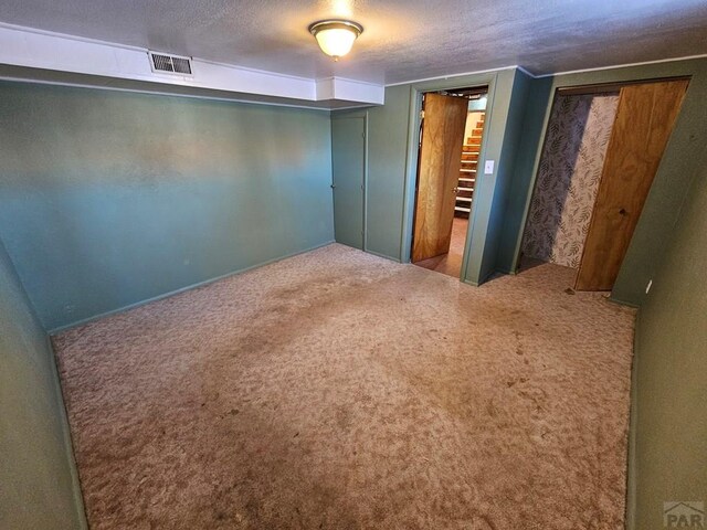 carpeted bedroom with multiple closets, visible vents, and a textured ceiling