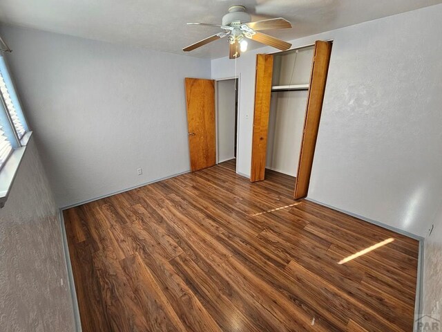 unfurnished bedroom featuring ceiling fan, a closet, and dark wood-style flooring