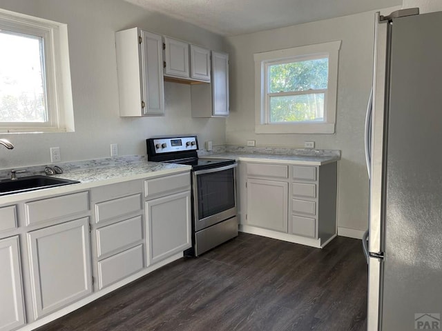 1540 E 13th St, Pueblo, CO 81001 - kitchen with stainless steel appliances, a sink, light countertops, dark wood-style floors, and white cabinetry