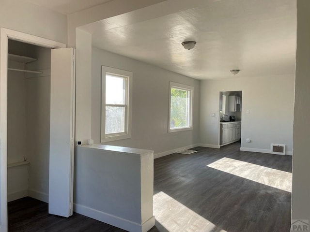 1540 E 13th St, Pueblo, CO 81001 - unfurnished living room featuring dark wood-type flooring, baseboards, and a sink