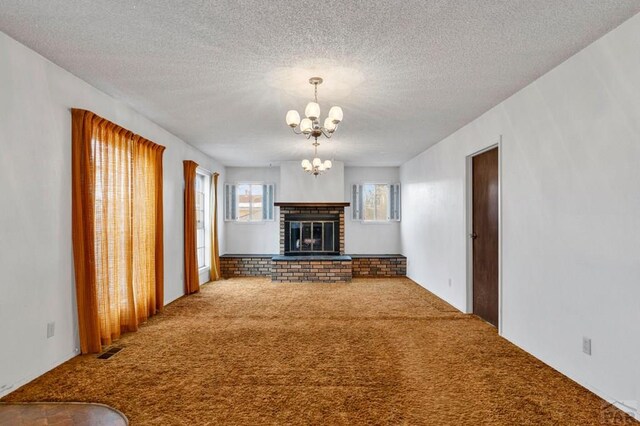 unfurnished living room featuring visible vents, a textured ceiling, carpet flooring, a fireplace, and a notable chandelier