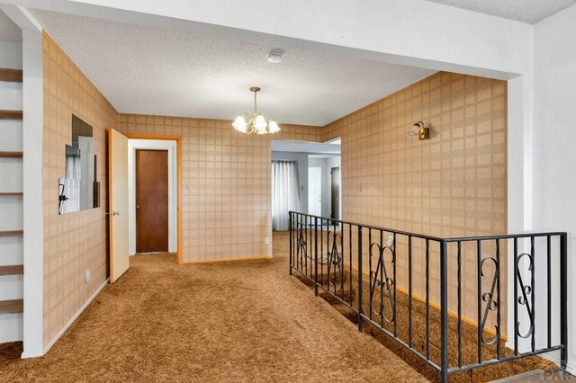 corridor with wallpapered walls, carpet, and a textured ceiling