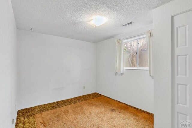 unfurnished room featuring a textured ceiling and visible vents