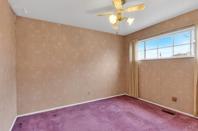 spare room featuring ceiling fan, carpet floors, visible vents, and baseboards