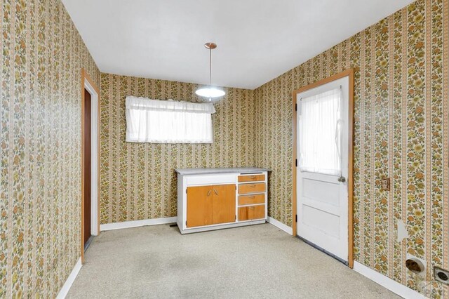 unfurnished dining area featuring baseboards and wallpapered walls