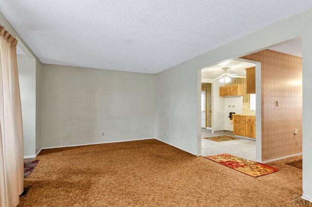 empty room featuring ceiling fan, a textured ceiling, and light colored carpet