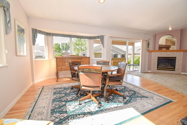 dining room featuring wood finished floors, a tile fireplace, baseboards, and recessed lighting