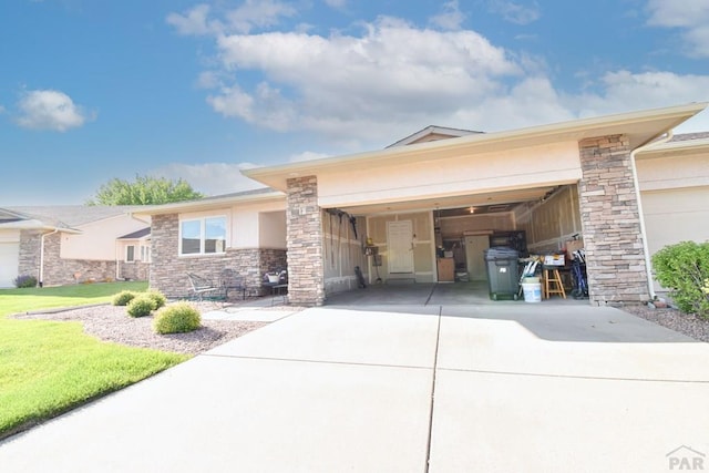 view of front of house featuring driveway, stone siding, a garage, and a front yard