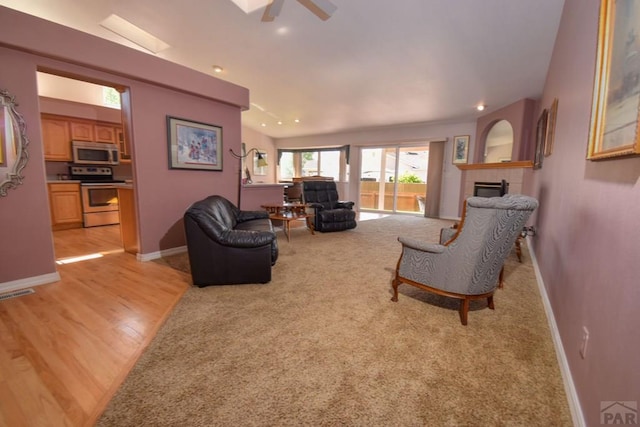 living area with baseboards, a ceiling fan, light wood-style flooring, a tiled fireplace, and recessed lighting