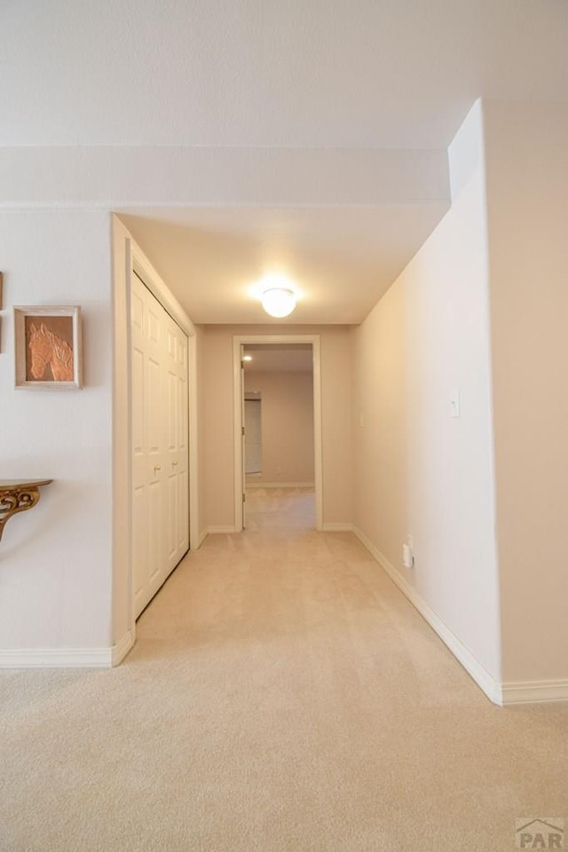hall featuring light colored carpet and baseboards