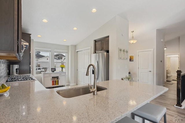16840 New Autum Dr, Monument, CO 80132 - kitchen featuring stainless steel fridge with ice dispenser, a sink, dark brown cabinetry, a breakfast bar area, and vaulted ceiling
