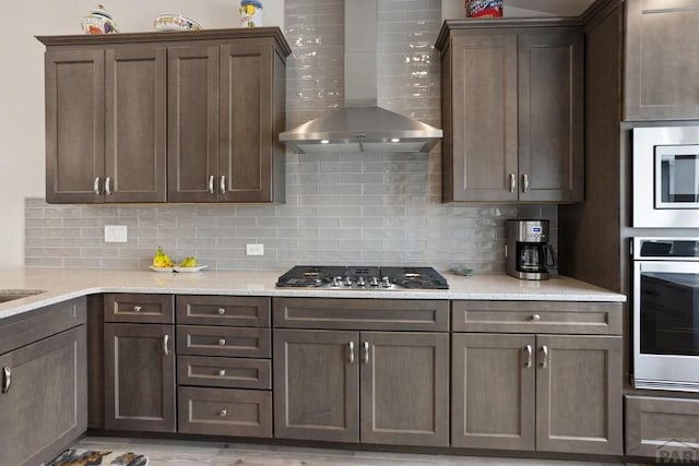 16840 New Autum Dr, Monument, CO 80132 - kitchen with wall chimney exhaust hood, appliances with stainless steel finishes, decorative backsplash, dark brown cabinets, and light stone countertops