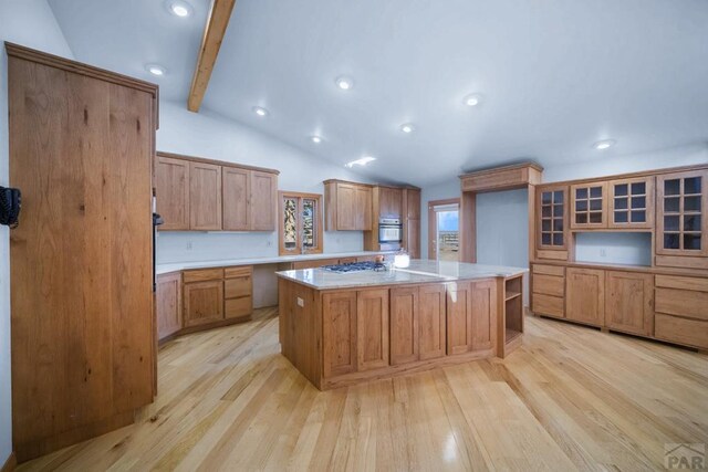 kitchen featuring light stone countertops, light wood-style flooring, stainless steel gas stovetop, and a kitchen island