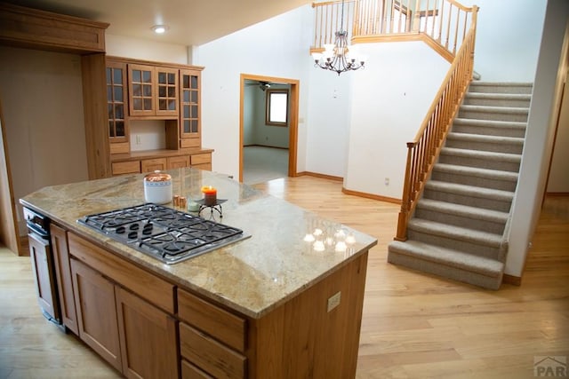 kitchen featuring light wood finished floors, stainless steel gas stovetop, a kitchen island, and light stone counters