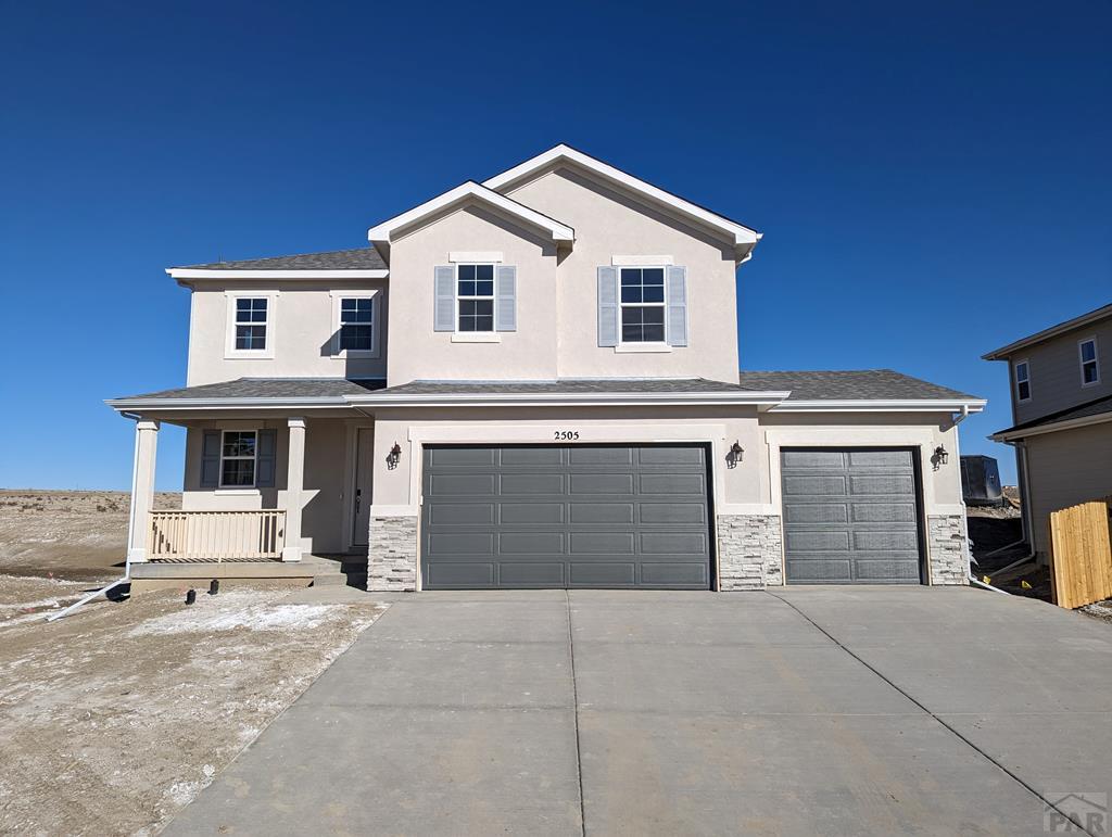 view of front of home with stucco siding, a porch, an attached garage, stone siding, and driveway