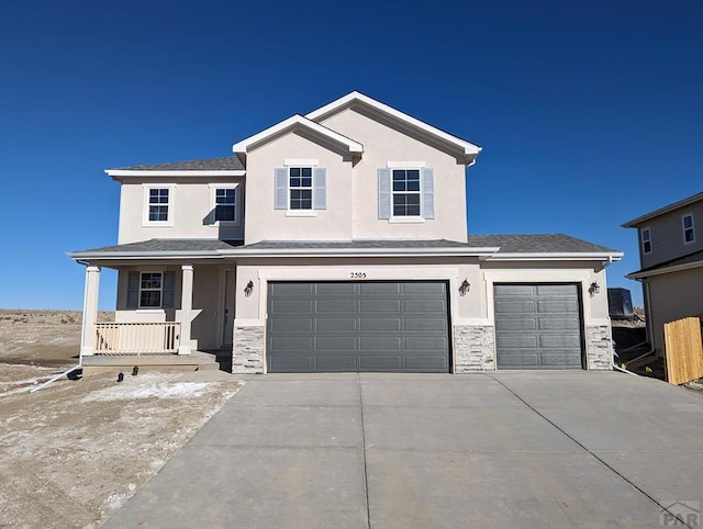 view of front of home with stucco siding, a porch, an attached garage, stone siding, and driveway