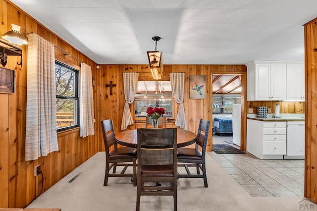 dining room featuring light tile patterned floors, light colored carpet, visible vents, and wooden walls