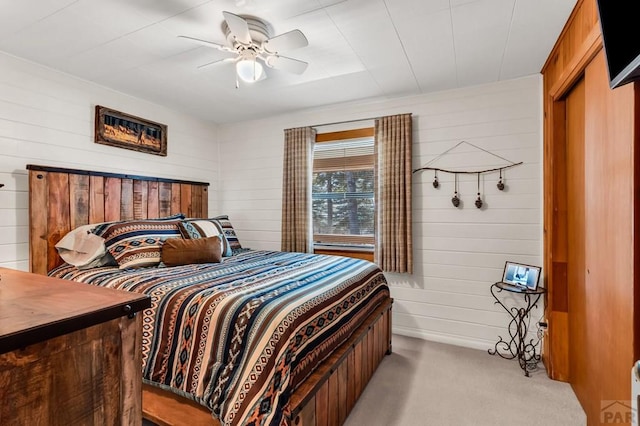 bedroom with wood walls, ceiling fan, and light colored carpet