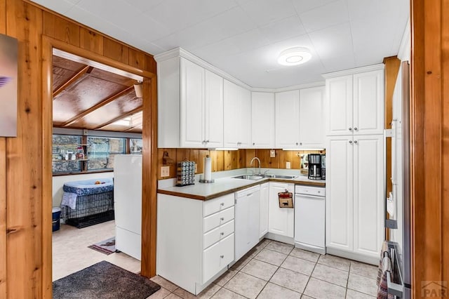 kitchen with wooden walls, white dishwasher, white cabinetry, and light countertops