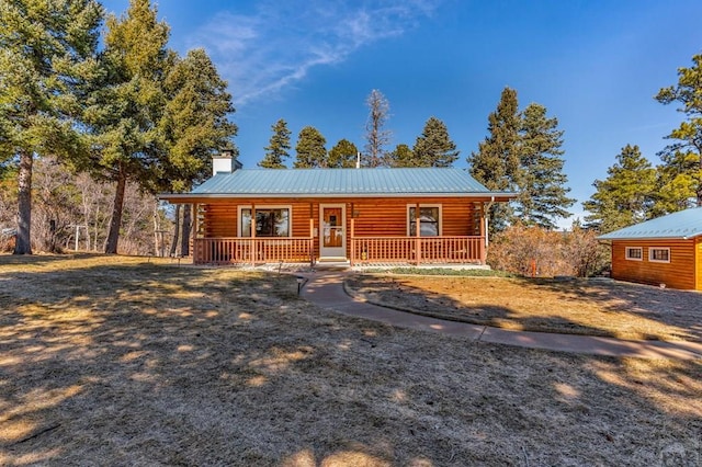 log cabin featuring covered porch, a chimney, log siding, and metal roof