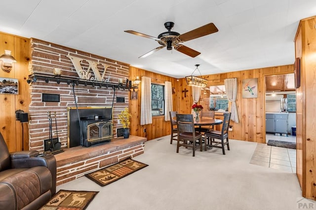 carpeted living room featuring a ceiling fan, a wood stove, and wooden walls