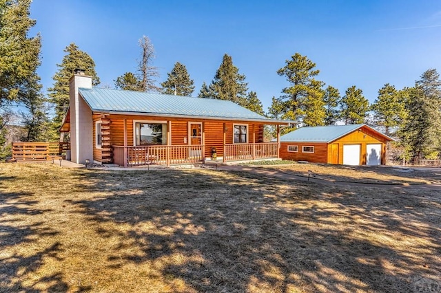 log cabin featuring a garage, a chimney, metal roof, covered porch, and an outdoor structure