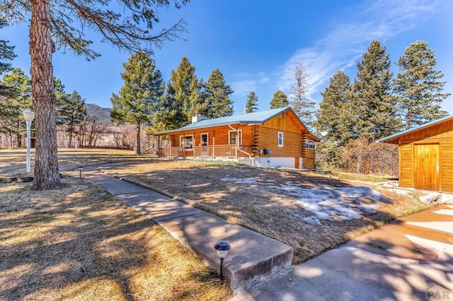 view of front of house with covered porch, a chimney, and log exterior